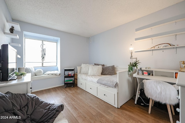 bedroom with a textured ceiling and light hardwood / wood-style flooring