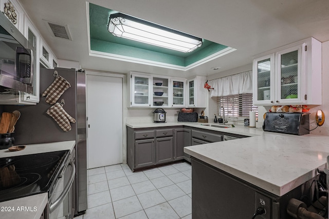 kitchen with white cabinets, gray cabinets, sink, and a tray ceiling