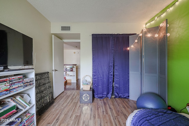 bedroom with a textured ceiling and light hardwood / wood-style flooring