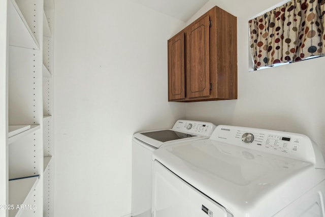 clothes washing area featuring cabinets and washer and clothes dryer