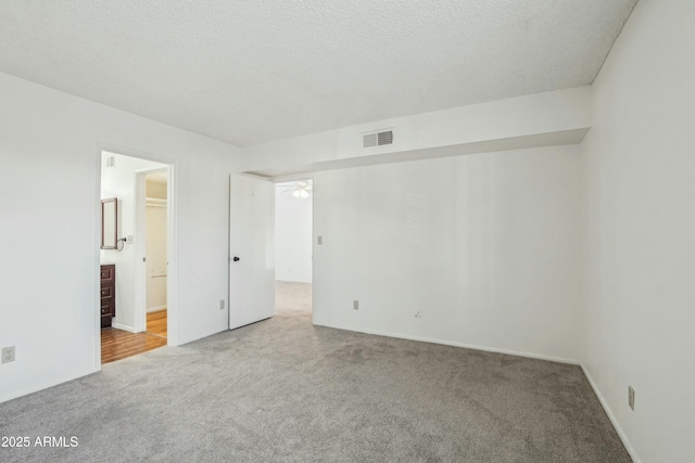 carpeted empty room with a textured ceiling