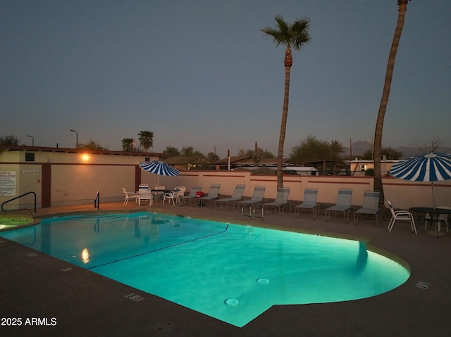 pool at dusk featuring a patio area