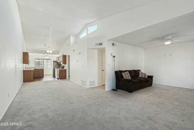 living room with sink, light colored carpet, high vaulted ceiling, a textured ceiling, and ceiling fan