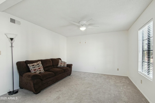 carpeted living room with a textured ceiling and ceiling fan