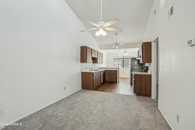 kitchen featuring sink, tasteful backsplash, range, high vaulted ceiling, and carpet