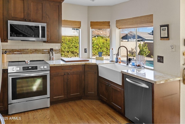 kitchen featuring stainless steel appliances, sink, a wealth of natural light, and light stone counters