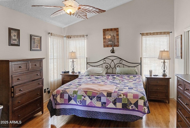 bedroom with lofted ceiling, ceiling fan, light hardwood / wood-style floors, and a textured ceiling