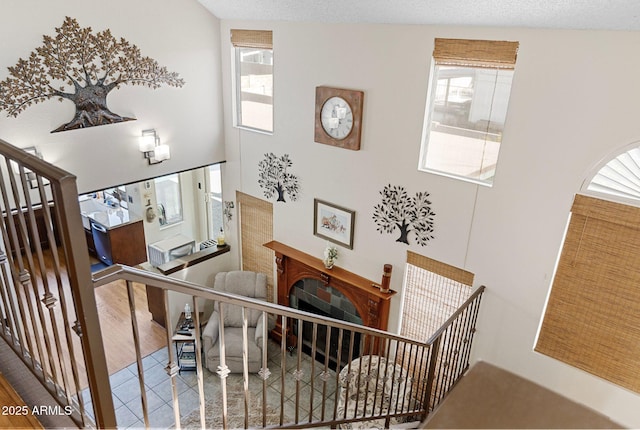 staircase with a high ceiling, plenty of natural light, and a textured ceiling