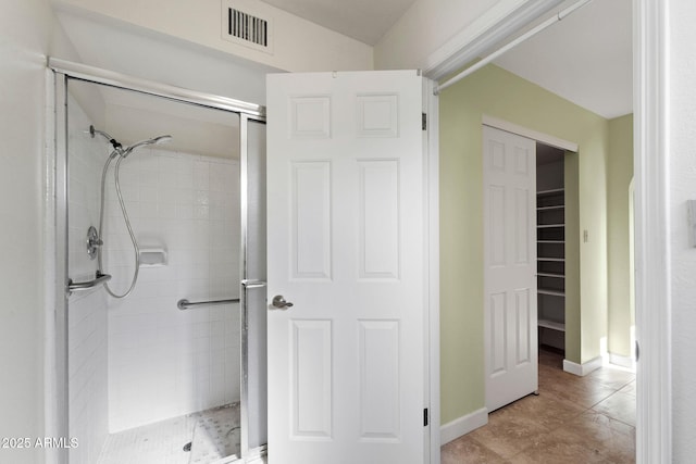 bathroom with a tile shower and tile patterned floors