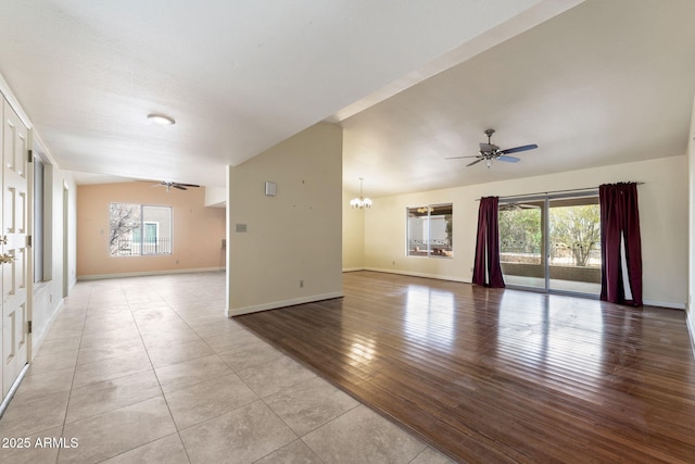 unfurnished room with ceiling fan with notable chandelier and light tile patterned floors