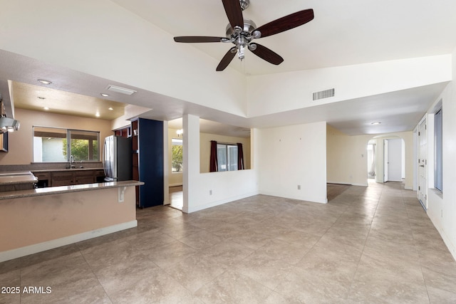 unfurnished living room featuring ceiling fan, sink, and high vaulted ceiling