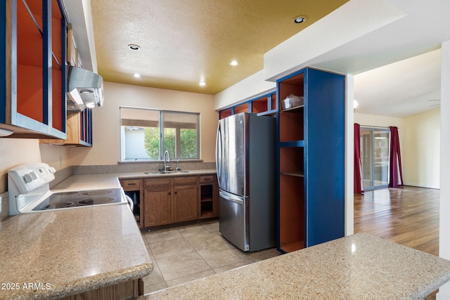 kitchen with white electric range, ventilation hood, sink, stainless steel fridge, and light tile patterned floors