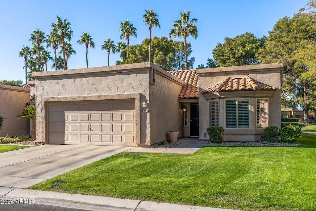 mediterranean / spanish home featuring a front yard and a garage