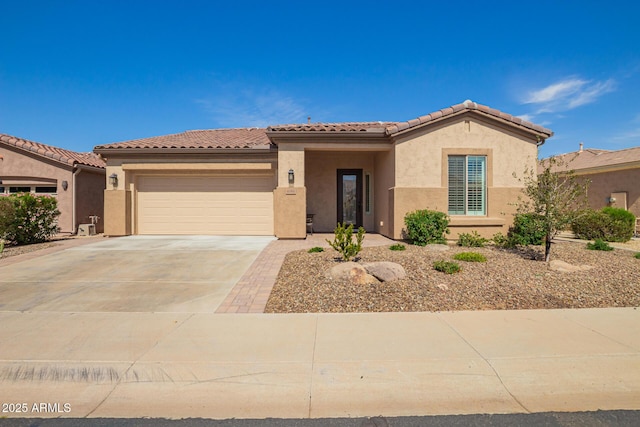 mediterranean / spanish home with stucco siding, a garage, concrete driveway, and a tiled roof