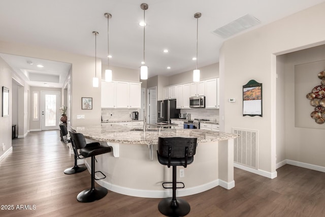 kitchen with white cabinets, visible vents, backsplash, and stainless steel appliances