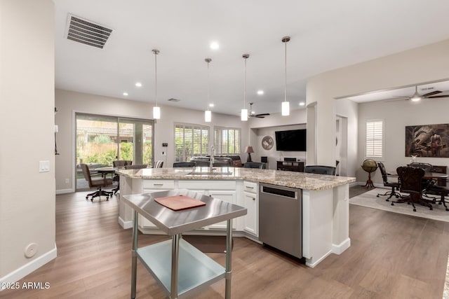 kitchen with visible vents, open floor plan, dishwasher, light wood-style floors, and a sink