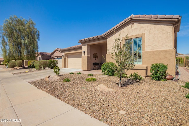 mediterranean / spanish-style home with stucco siding, concrete driveway, an attached garage, and a tiled roof