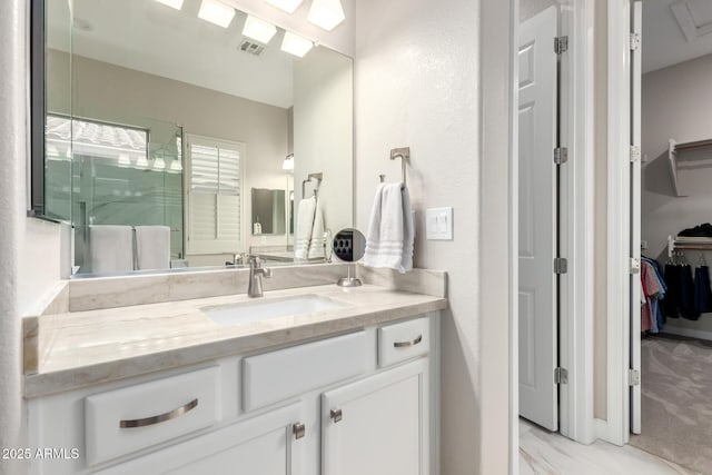 bathroom with visible vents, a walk in closet, a stall shower, marble finish floor, and vanity
