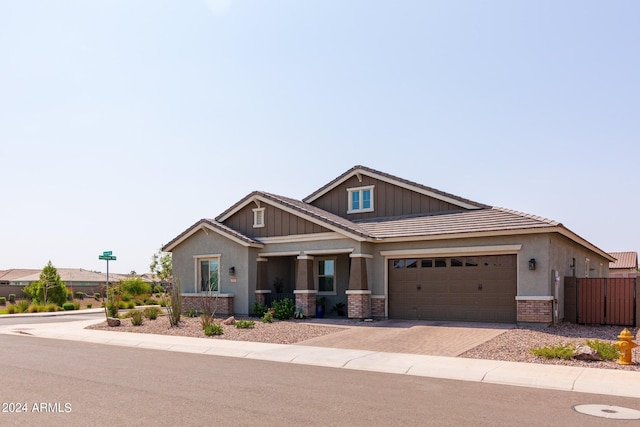 craftsman-style home featuring stucco siding, decorative driveway, fence, a garage, and a tiled roof