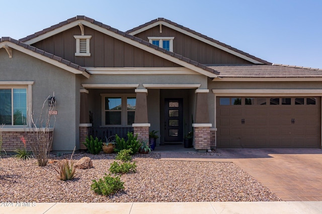 craftsman-style home with stucco siding, a tiled roof, decorative driveway, and a garage