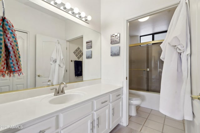 bathroom featuring combined bath / shower with glass door, vanity, toilet, and tile patterned floors