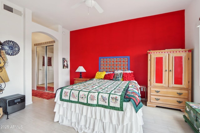 bedroom featuring arched walkways, visible vents, an accent wall, ceiling fan, and baseboards