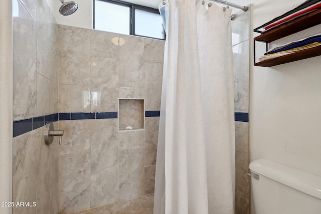 bathroom with a tile shower and toilet