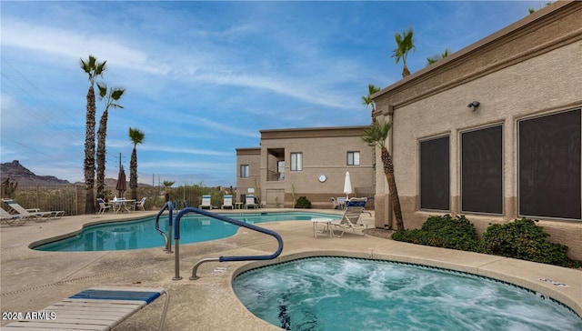 community pool featuring a patio, fence, and a hot tub