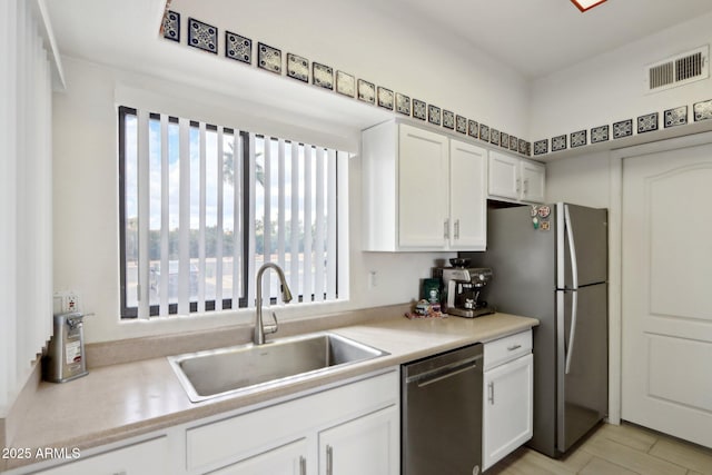 kitchen with a sink, visible vents, white cabinetry, light countertops, and appliances with stainless steel finishes