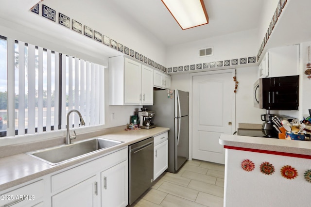 kitchen with visible vents, stainless steel appliances, light countertops, white cabinetry, and a sink