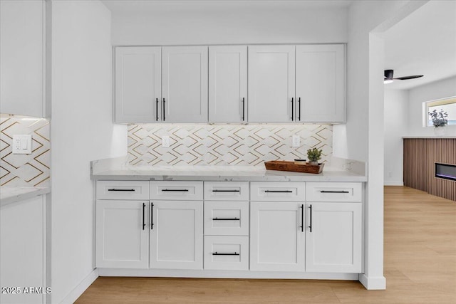 bar featuring baseboards, backsplash, and light wood finished floors