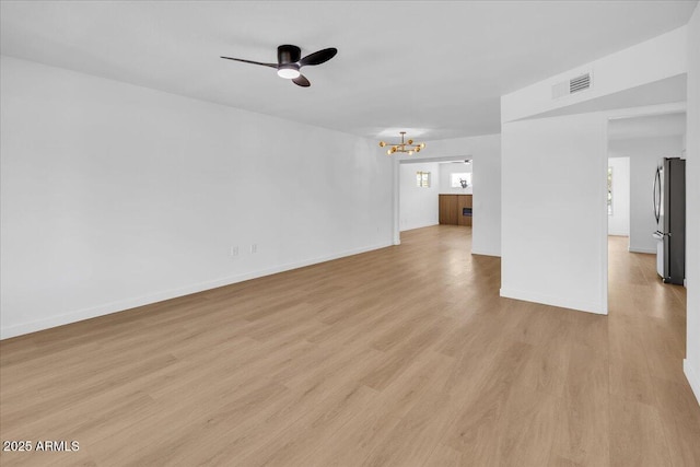 unfurnished living room featuring light wood-type flooring, baseboards, visible vents, and ceiling fan with notable chandelier