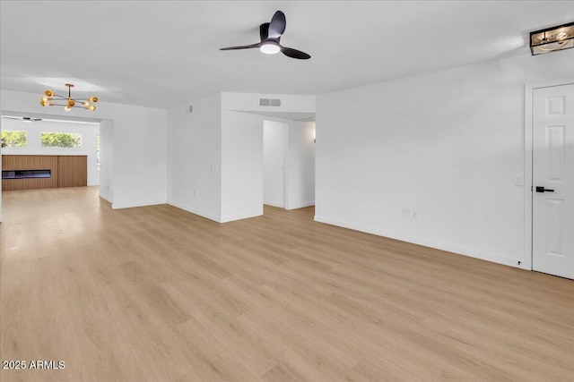 unfurnished living room with visible vents, baseboards, light wood-style flooring, and ceiling fan with notable chandelier