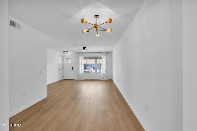 unfurnished living room with a chandelier, visible vents, light wood finished floors, and baseboards