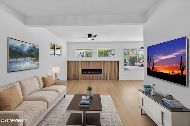 living area with a ceiling fan, light wood-style flooring, and a fireplace