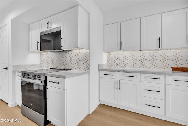 kitchen featuring light wood finished floors, tasteful backsplash, light stone counters, stainless steel range with electric cooktop, and white cabinetry