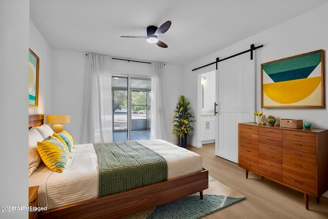 bedroom with a ceiling fan, light wood-style floors, ensuite bathroom, a barn door, and access to outside