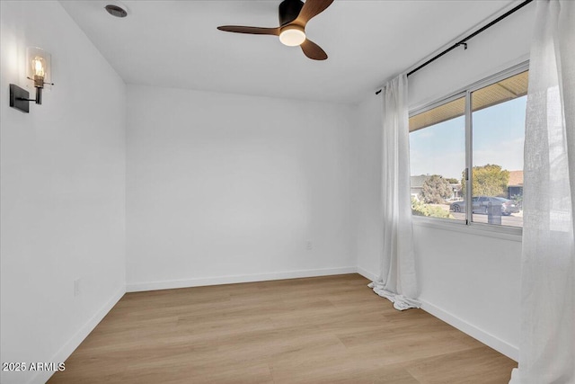 empty room featuring ceiling fan, light wood-type flooring, and baseboards