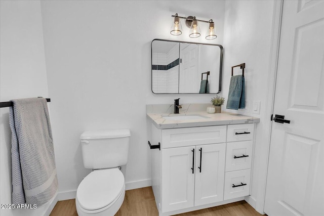 bathroom featuring toilet, wood finished floors, baseboards, walk in shower, and vanity