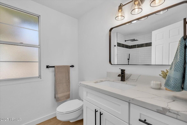 full bathroom featuring baseboards, toilet, tiled shower, wood finished floors, and vanity