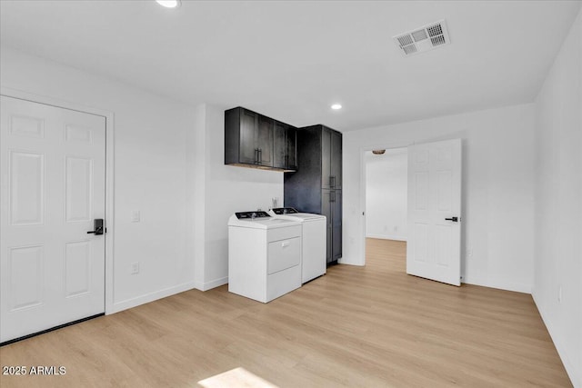 kitchen with washing machine and clothes dryer, visible vents, light wood finished floors, and light countertops