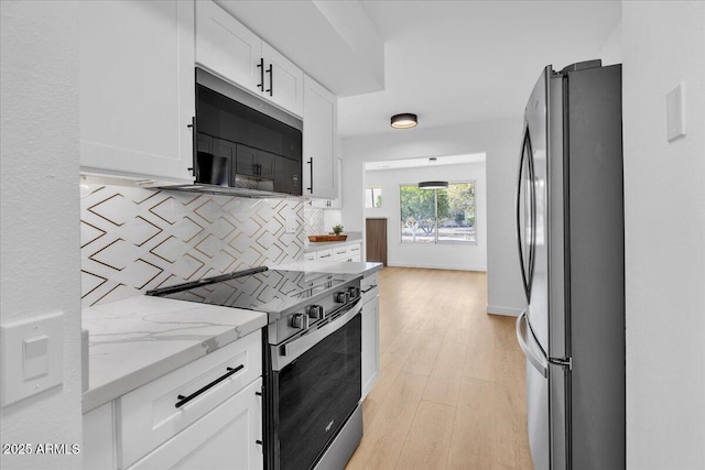 kitchen with range with electric cooktop, light stone counters, freestanding refrigerator, white cabinets, and decorative backsplash