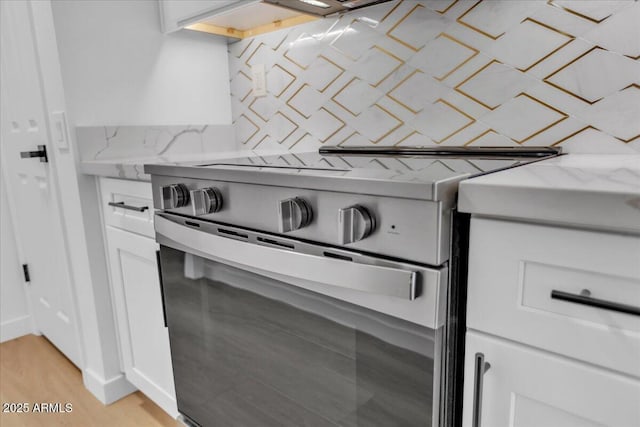 room details featuring white cabinetry, light wood-style flooring, light stone countertops, and range with electric stovetop