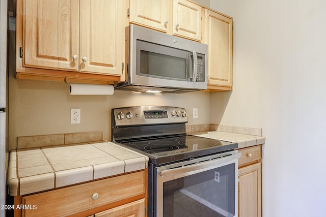 kitchen with tile countertops, light brown cabinets, and stainless steel appliances