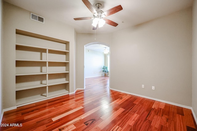 spare room with hardwood / wood-style floors, ceiling fan, and built in shelves