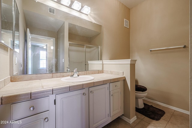 bathroom featuring tile patterned flooring, vanity, toilet, and an enclosed shower