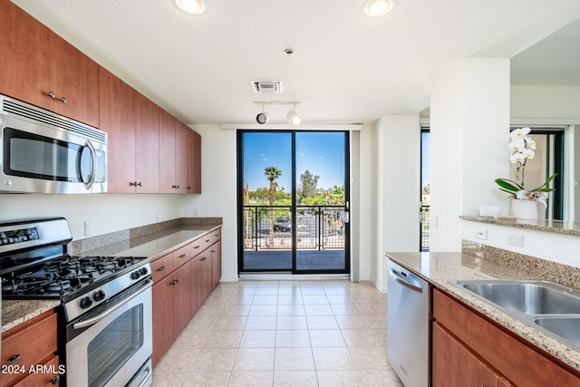 kitchen featuring light stone counters, light tile floors, sink, stainless steel appliances, and track lighting