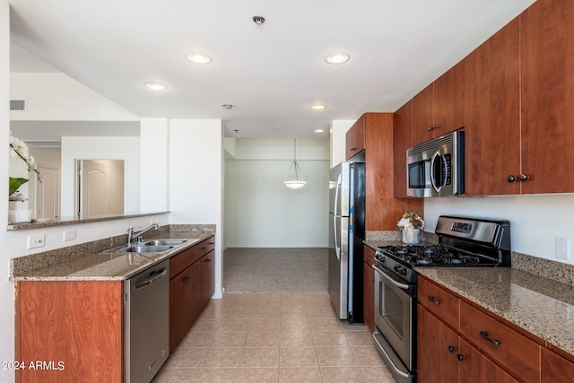 kitchen featuring stone countertops, light carpet, sink, decorative light fixtures, and stainless steel appliances