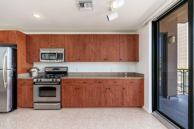 kitchen with appliances with stainless steel finishes, light tile floors, and track lighting