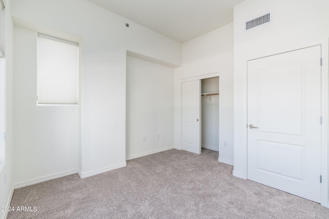 unfurnished bedroom featuring light colored carpet and a closet